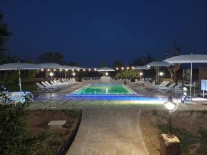a swimming pool with chairs and umbrellas at night at B&b Casina Il Mandorlo in Nardò