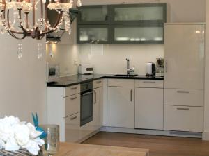 a kitchen with white cabinets and a chandelier at Ferienwohnung Luxus & Lifestyle in Lindau