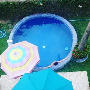 Una donna sta in piedi in una piscina con un ombrellone di Delfin B&B a La Cruz de Huanacaxtle