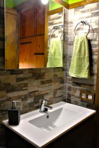 ein Badezimmer mit einem Waschbecken, einem Spiegel und grünen Handtüchern in der Unterkunft Refugio La Cabrera in Mont-ral