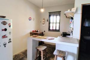 cocina con encimera blanca y 2 taburetes en Casa de Campo Diamantina MG, en Diamantina