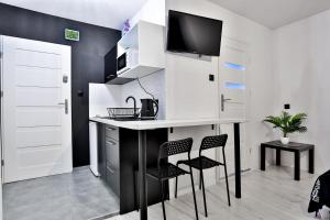 a kitchen with a counter and two chairs and a table at Apartamenty czarna perła in Szaflary