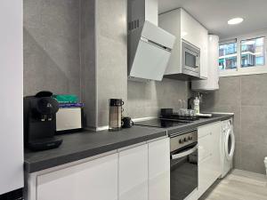 una cucina con armadietti bianchi, piano cottura e forno a microonde di Apartamento moderno Centro de Marbella a Marbella
