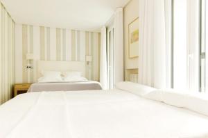 2 weiße Betten in einem Zimmer mit Fenster in der Unterkunft Hotel Sauce in Saragossa