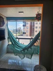 a hammock in a room with a large window at Apartamento Capão da Canoa com garagem in Capão da Canoa