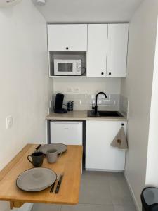 una pequeña cocina con armarios blancos y una mesa de madera. en studio climatisé, en Carnoules