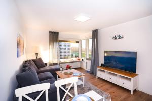 uma sala de estar com um sofá e uma televisão de ecrã plano em Hanseat I Whg 34 em Grömitz
