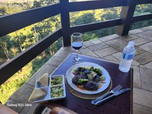 una mesa con un plato de comida y una copa de vino en Vista Linda Hotel, en Itatiaia