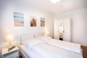 um quarto branco com 2 camas e uma mesa em Hanseat I Whg 34 em Grömitz