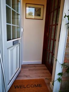 a door leading to a hallway with a welcome mat at Impeccable 1-Bed Lodge in Eastleigh in Eastleigh