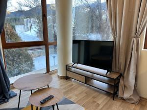 a living room with a flat screen tv and two tables at Pine Tree - charming apartment in Bansko