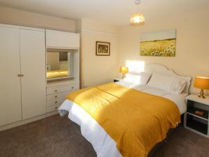 a bedroom with a large bed with a yellow blanket at The Stables in Wigton