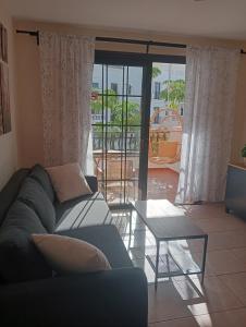 ein Wohnzimmer mit einem Sofa und einem Tisch in der Unterkunft Greatly located apartment with heated pool, Los Cristianos in Los Cristianos