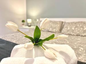 un jarrón lleno de flores blancas en una cama en Archivio 32 Neapolitan Apartment, en Nápoles