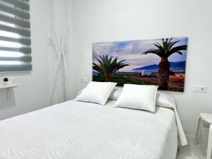 a bedroom with a white bed with two palm trees at Alcalá Retreat: Ocean View & Modern Comfort in Alcalá