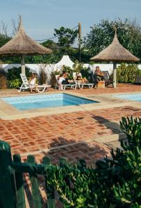 un grupo de personas sentadas alrededor de una piscina con sombrillas en Los Horneros Bungalows, en La Paloma