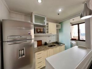 una cocina con nevera de acero inoxidable y armarios blancos en Flat V. Olimpia 02 DTS, ar cond. todos ambientes en São Paulo