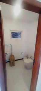een witte badkamer met een toilet en een raam bij Paraíso do sul - Shangrilá in Pontal do Paraná