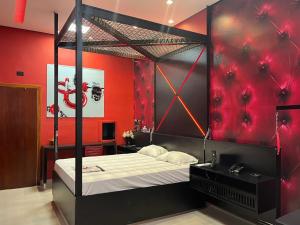 a bedroom with a canopy bed with red walls at Motel Stilo - Adults Only in Contagem