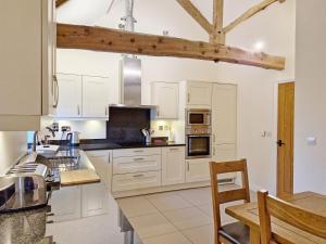 a kitchen with white cabinets and a wooden beam at The Run, West Lavant in Chichester