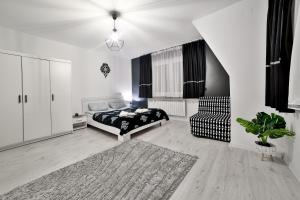 a white bedroom with a bed and a chair at Apartament Czarna Perła z balkonem in Szaflary