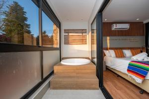 a bedroom with a tub and a bed and a window at Wanderlust Experience Hotel BW Signature Collection OFICIAL in Campos do Jordão