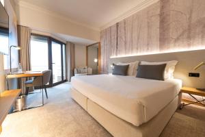サント・ティルソにあるCidnay Santo Tirso - Charming Hotel & Executive Centerの大きなベッドとデスクが備わるホテルルームです。