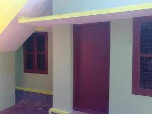 een kamer met 2 ramen en een rode deur bij Unnis Old Home in Adūr