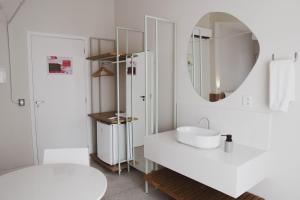 a white bathroom with a sink and a mirror at Liiv Hub - Natal PontaNegra in Natal +49 photos