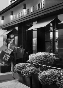 a woman sitting outside of a building holding shopping bags at H&ocirc;tel de Lille - Saint-Germain des Pr&egrave;s in Paris