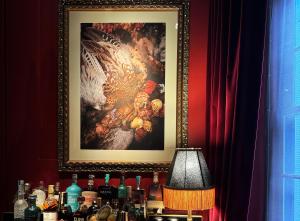 a picture of a painting on a wall with a table with bottles at Chateau Denmark London in London