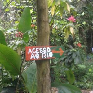a street sign on a tree in a forest at Hostel e Camping Rio das Pedras in Camburi