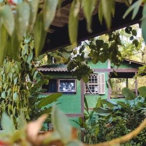 a green house with a window in a yard at Hostel e Camping Rio das Pedras in Camburi