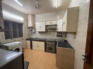 La cuisine est équipée de placards blancs et d'un four avec plaques de cuisson. dans l'établissement Bungalow at Porvorim, Panaji, à Panaji