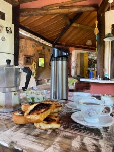 a table with bread and cups and a coffee maker at Casa Atelie Bangue in Ilhabela