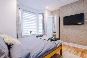 a bedroom with a bed and a flat screen tv at 4 Bedroom Victorian House in Manchester