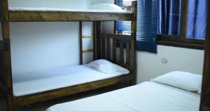 two bunk beds in a dorm room with white sheets at Hotel Campestre El Refugio in Guaduas