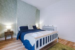 a bedroom with a blue and white bed and a table at 4 Bedroom Victorian House in Manchester