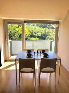 uma sala de jantar com mesa e cadeiras e uma grande janela em Duplex avec superbe vue boisée em Esneux