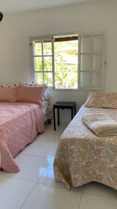 布希奧斯的住宿－Casa em Búzios，白色的客房设有两张床和窗户。