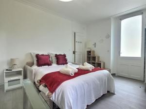 1 dormitorio blanco con 2 camas y almohadas rojas en Cosy des Rêves *Paris*Disney*, en Croissy-Beaubourg