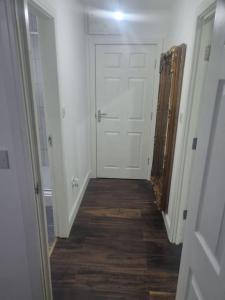 einen Flur mit weißer Tür und Holzboden in der Unterkunft 1 Bedroom Apartment in Daventry