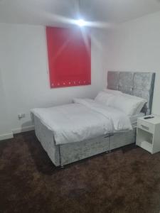 a bed in a room with a red painting on the wall at 1 Bedroom Apartment in Daventry