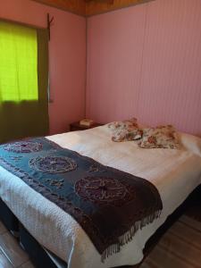 ein Schlafzimmer mit einem Bett mit einer Decke darauf in der Unterkunft Cabaña Martita in Pucón