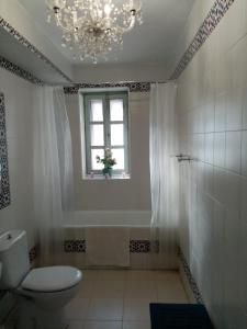 baño con aseo, ventana y lámpara de araña en Casa Aracena "La Capilla de Aracenilla", en Aracena