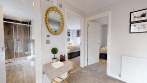 a bathroom with a mirror and a bedroom with a bed at The Stratford Suite Dunara 6 in Leamington Spa