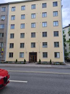 un edificio con un coche rojo estacionado frente a él en Pikkuhuoneisto loistosijainnilla Töölössä en Helsinki