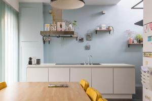 a kitchen with white cabinets and a wooden table at Lightful architectural house in Ghent