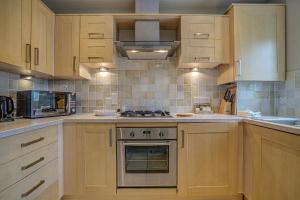 a kitchen with wooden cabinets and a stove top oven at The Vanbrugh Suites in Oxford