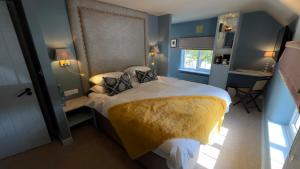 a bedroom with a large bed with a yellow blanket at The Bittescombe Inn in Upton